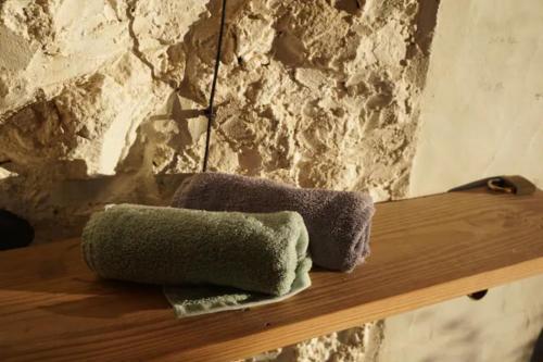 due asciugamani seduti su una mensola in legno accanto a un muro di pietra di Tiny House Vogelnest a Puntagorda