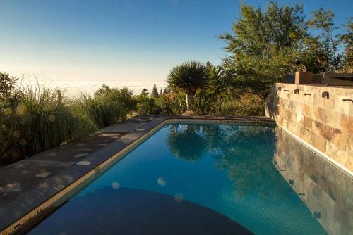 a swimming pool in a yard with a brick wall at Pool Finca La Placita in Puntagorda