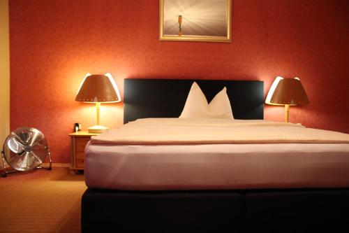 a bedroom with a bed with red walls and two lamps at Occhipinti Passione - Restaurant & Hotel - Weyhausen in Weyhausen