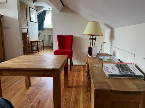 uma sala de estar com uma mesa de madeira e uma cadeira vermelha em Bed en Breakfast De Kees em Eersel