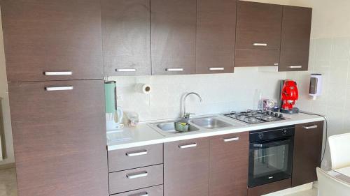 cocina con armarios de madera, fregadero y fogones en TDC Home, en Vallo della Lucania