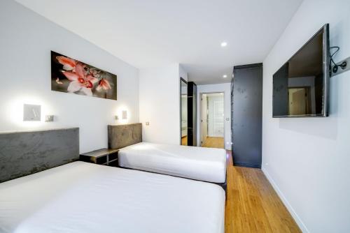 deux lits dans une chambre aux murs blancs dans l'établissement Appartements Croisette Grand Hôtel, à Cannes