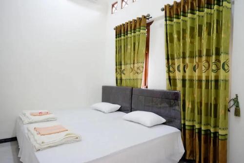 una camera con due letti con tende verdi e gialle di Griya Mataram Kotagede Mitra RedDoorz a Yogyakarta