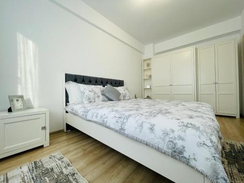 een witte slaapkamer met een bed en een witte kast bij Luxury Apartment with Sunset View Palas in Iaşi