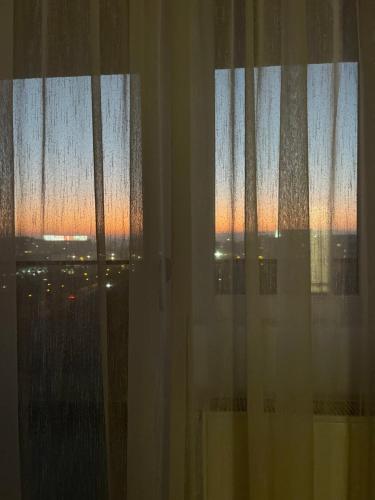 um quarto com uma janela com vista para o pôr-do-sol em Luxury Apartment with Sunset View Palas em Iaşi