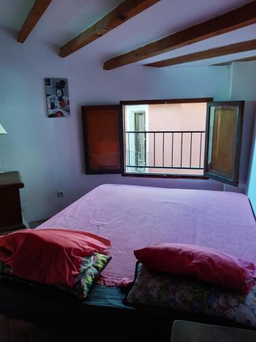 Schlafzimmer mit einem Bett mit roten Kissen und einem Fenster in der Unterkunft Grand appart 4,6,8 personnes vue directe sur mer in Villajoyosa