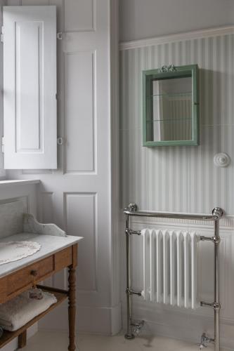 a bathroom with a radiator and a mirror on the wall at Le Logis d'Equilly in Équilly