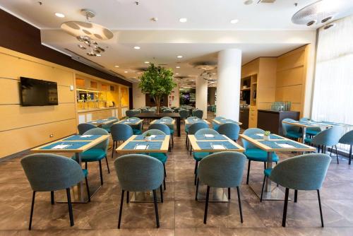 a restaurant with tables and chairs in a room at Ramada Plaza by Wyndham Milano in Milan