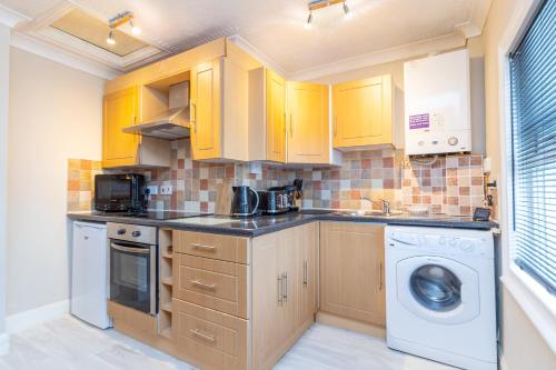 a kitchen with yellow cabinets and a washer and dryer at City Centre Convenient Contractor Stay With Free Parking and Free Wifi in Bedford