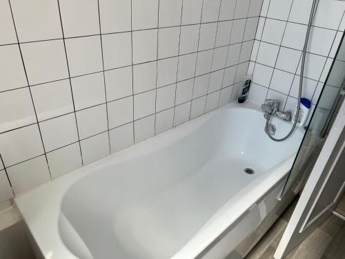 L'oasis de l'Yonne في Migennes: حوض استحمام أبيض في حمام به بلاط أبيض