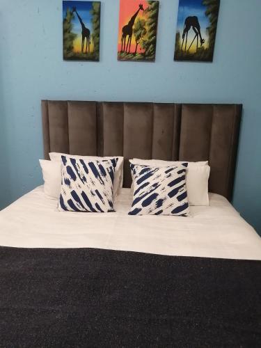 - un lit avec quatre oreillers et des photos de girafes dans l'établissement The Don Apt, Greenstone, à Edendale