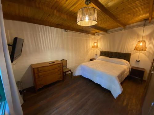 a bedroom with a bed and a dresser and a television at CASA DE CAMPO POTRERILLOS in Potrerillos