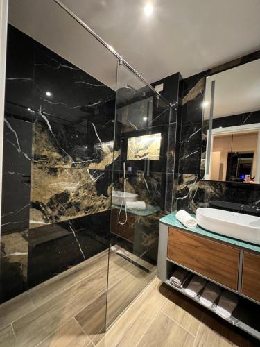 a bathroom with a sink and a glass shower at Domus Hotel & Apartments in Shëngjin