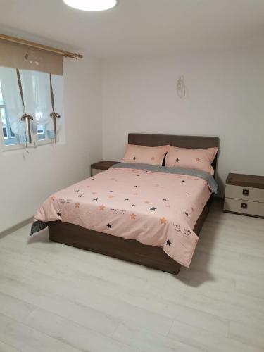 a bedroom with a bed with pink sheets and pillows at Fontana Erdélyi Vendégház 2 in Satu Mare