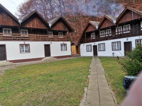 a row of wooden buildings with a grass yard at Fontana Erdélyi Vendégház 2 in Satu Mare
