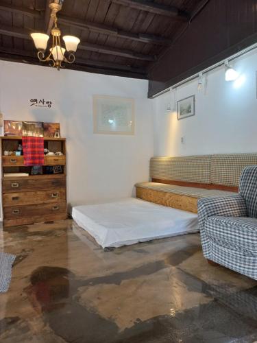 Pohang Youngildae Guesthouse في بوهانغ: غرفة نوم بسرير واريكة وخزانة