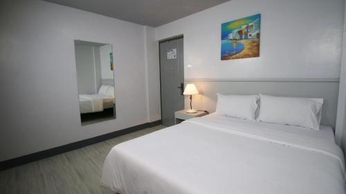 Schlafzimmer mit einem weißen Bett und einem Spiegel in der Unterkunft SANDS Hotel Nasugbu in Nasugbu