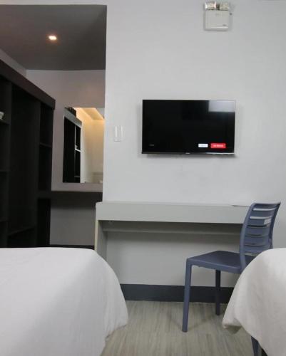 a bedroom with a bed and a chair and a tv at SANDS Hotel Nasugbu in Nasugbu