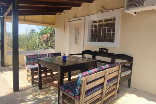 Olive Grove Cottage Skalani في Knossós: فناء مع طاولة وكراسي خشبية