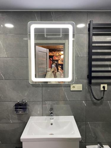 a person taking a picture of a sink in a bathroom at Vienna House in Yaremche