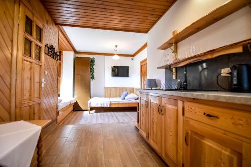a kitchen with wooden cabinets and a bed in a room at U Króla in Kościelisko
