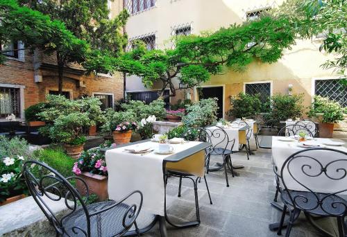 an outdoor patio with tables and chairs and trees at Sina Palazzo Sant'Angelo in Venice
