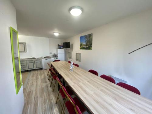 una sala de conferencias con una larga mesa de madera y sillas rojas en Gîte de groupe proche du Château, en Villandry