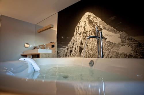 a bathroom with a tub with a picture of a mountain at Eiger Mountain & Soul Resort in Grindelwald
