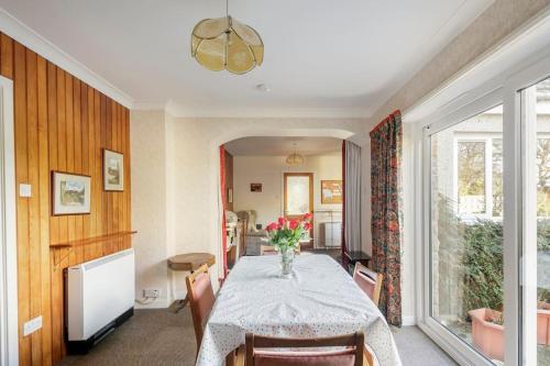 a dining room with a table with a vase of flowers on it at Bungalow in Spey Bay, Moray (Disabled Accessible) in Kingston