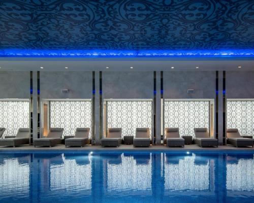 a pool with chairs and a ceiling with blue lights at InterContinental London - The O2 in London