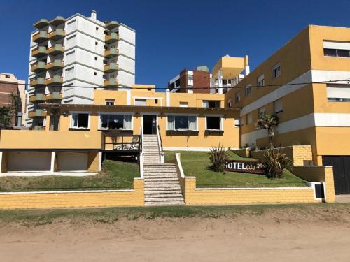 a yellow building with stairs in front of a building at City mar playa in Villa Gesell