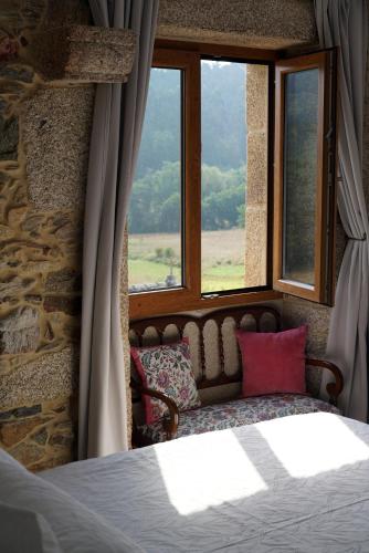 a bedroom with a bed and a window with a couch at Casa de Chica Ecoturismo in Lousame