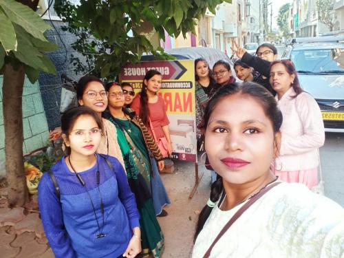 un grupo de mujeres frente a un cartel en Narmada Guest House en Indore