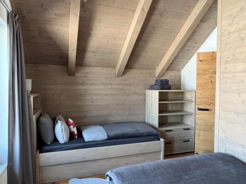 a bed in a room with a wooden wall at VILLA BOHEMIA - Boží Dar in Boží Dar