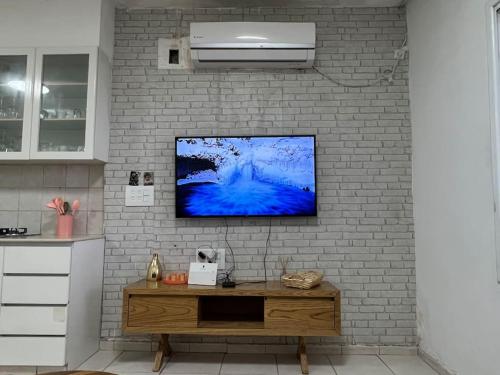 une télévision suspendue sur un mur en briques avec une table dans l'établissement Beach front! 2 bedrooms right on the boardwalk, à Tel Aviv