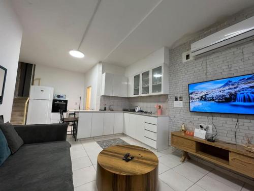 ein Wohnzimmer mit einem Sofa und eine Küche mit einem TV in der Unterkunft Beach front! 2 bedrooms right on the boardwalk in Tel Aviv