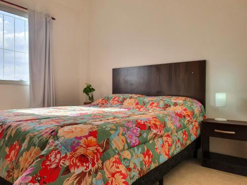 a bedroom with a bed with a floral bedspread at Médanos Negros Departamentos in San Juan