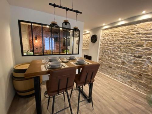 a dining room with a table and chairs and a stone wall at Bienvenue à l'Appart' de Louis ! in Dole