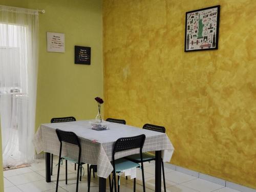 a dining room table with chairs and a yellow wall at Al Irfan Homestay Tmn SgDua Utama in Butterworth