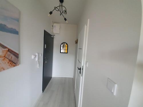 a hallway with white walls and a black door at Apartament Słoneczny Sienkiewicza 3A in Leszno