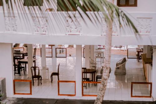 a palm tree in a room with tables and chairs at Twice Happy Beach Garden in Tangalle