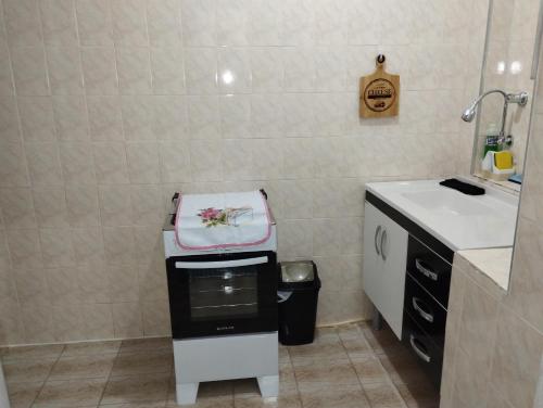 PRAIA ENSEADA - WI-FI e AR CONDICIONADO في غوارويا: حمام صغير مع مغسلة وغسالة ملابس