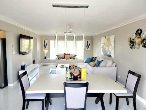 ein Wohnzimmer mit zwei weißen Tischen und Stühlen in der Unterkunft Brand New Luxurious Townhouse in Negril in Negril
