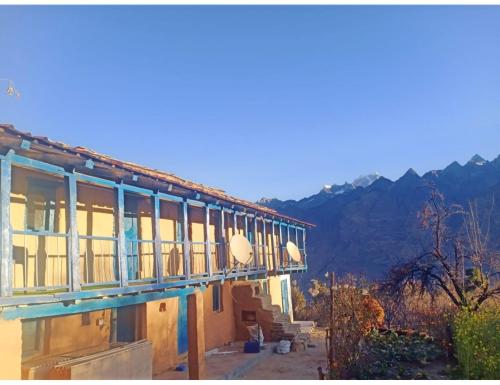 a building with windows with mountains in the background at Hotel Mud House Auli, Joshimath, in Joshīmath
