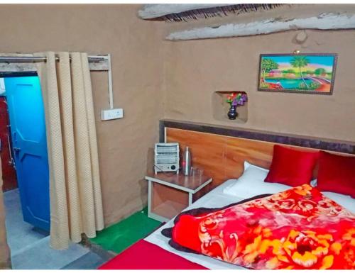 a bedroom with a bed with red pillows and a table at Hotel Mud House Auli, Joshimath, in Joshīmath