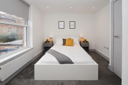 a white bedroom with a bed and a window at High spec 2 Bed apartment w/parking available in London