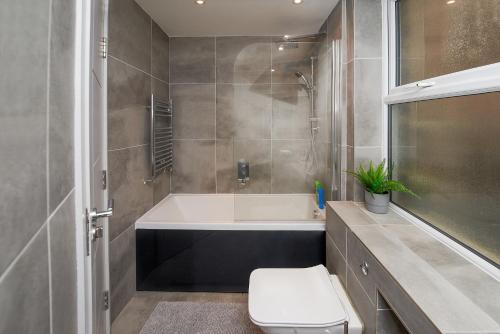 y baño con bañera y aseo. en High spec 2 Bed apartment w/parking available, en Londres