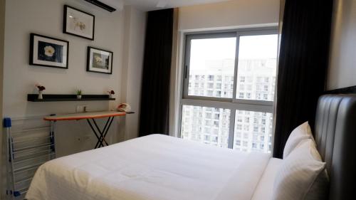 een slaapkamer met een wit bed en een raam bij RELOhomes Serviced Apartment in Mumbai