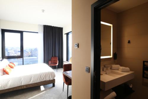 a bedroom with a bed and a sink and a mirror at Mercure Namur Hotel in Namur