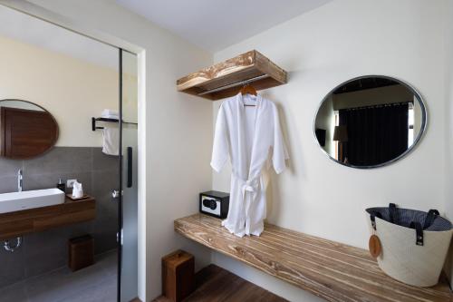 ein Badezimmer mit einem Spiegel und einem weißen Bademantel auf einem Regal in der Unterkunft Pradja Slumbung Villas in Nusa Penida
